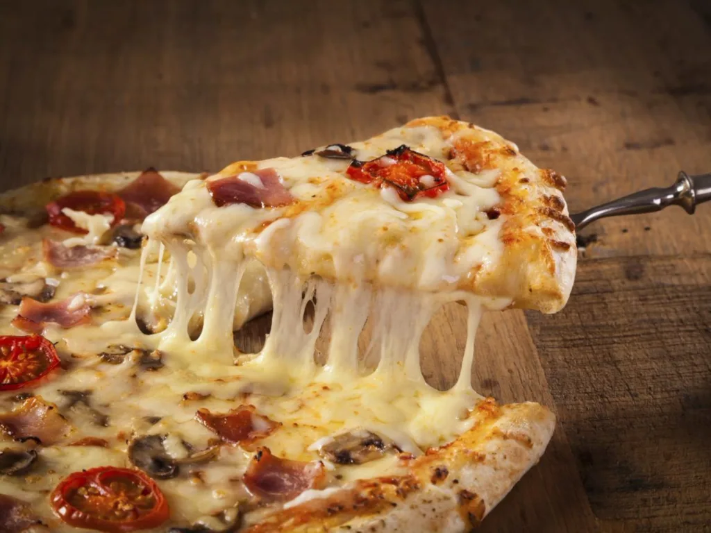 A slice of pizza taken from a pizza with plant-based cheese used